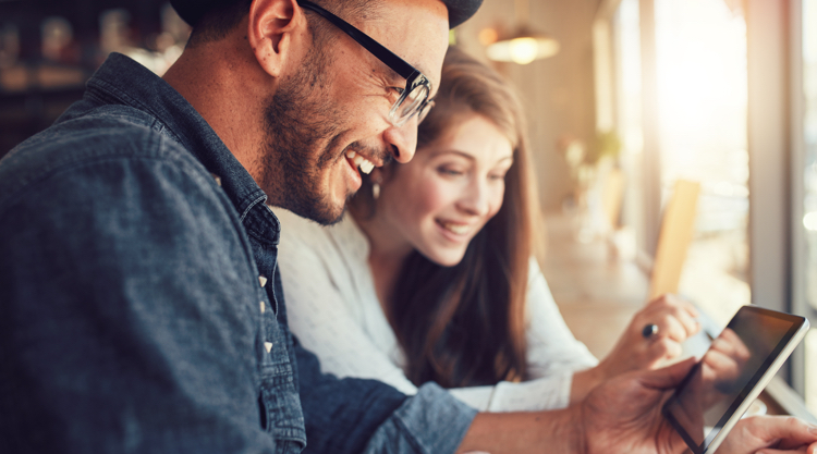 Two coworkers smiling while discussing work on a tablet