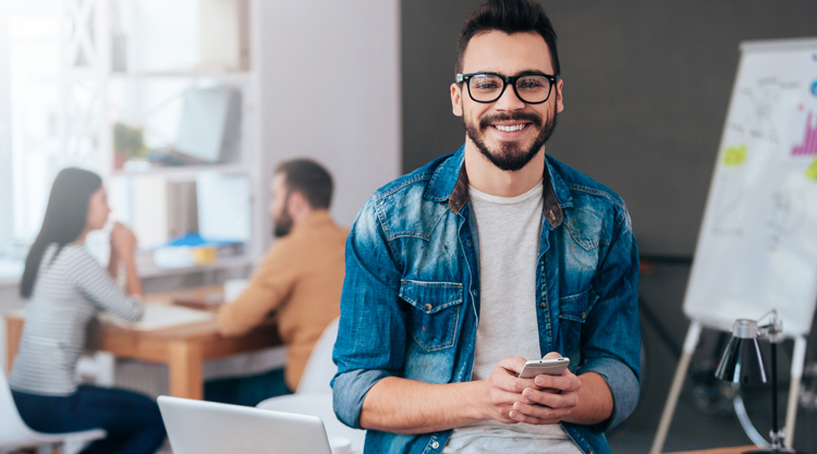 Man smiling at work holding phone