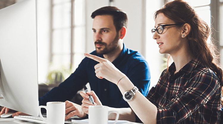 Two co-workers looking at desktop screen