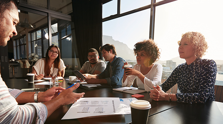 A group of people seated outside reading menus and drinking coffee
