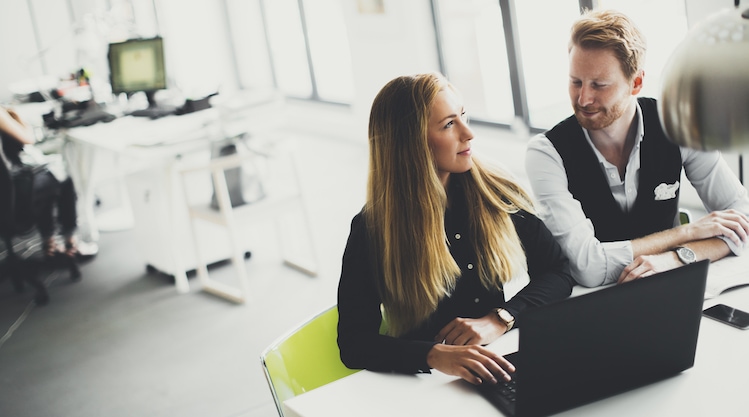 A man and woman seated next to each other in an office with a laptop in front of them