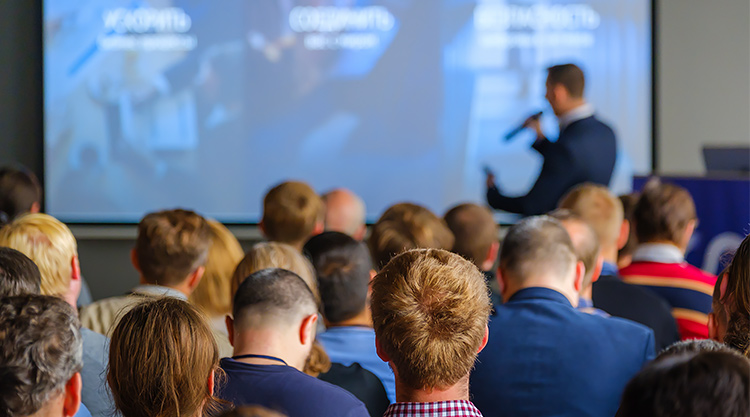 A crowd of people seated at a conference listening to the speaker