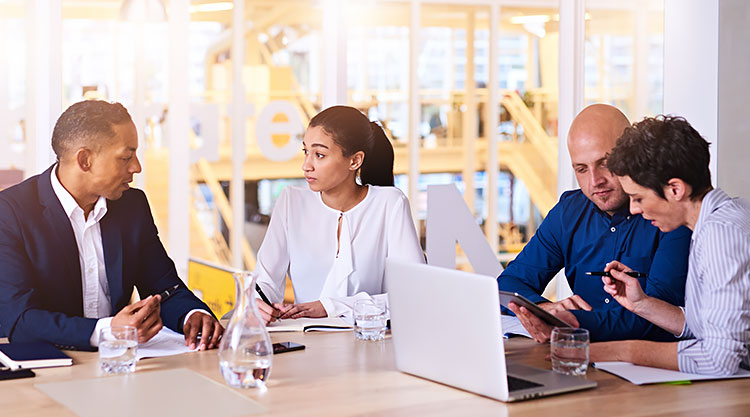 A group of coworkers seated at a table in an office building