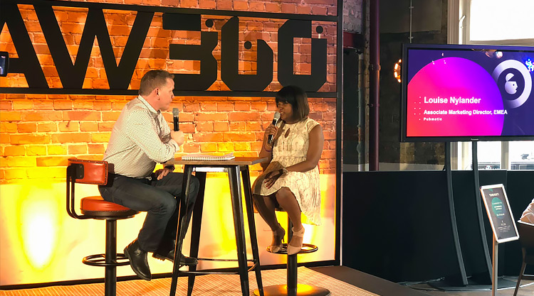 A man and woman are seated on stage with microphones.