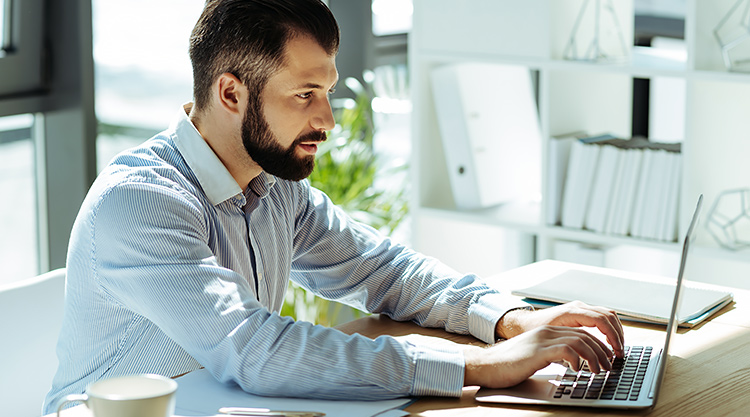 A man typing on his laptop while working in his home office