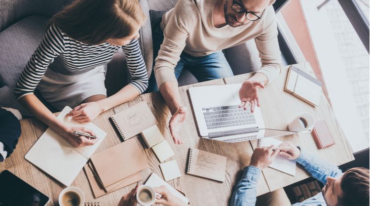 An overhead shot of a group of people working together and writing in a cafe