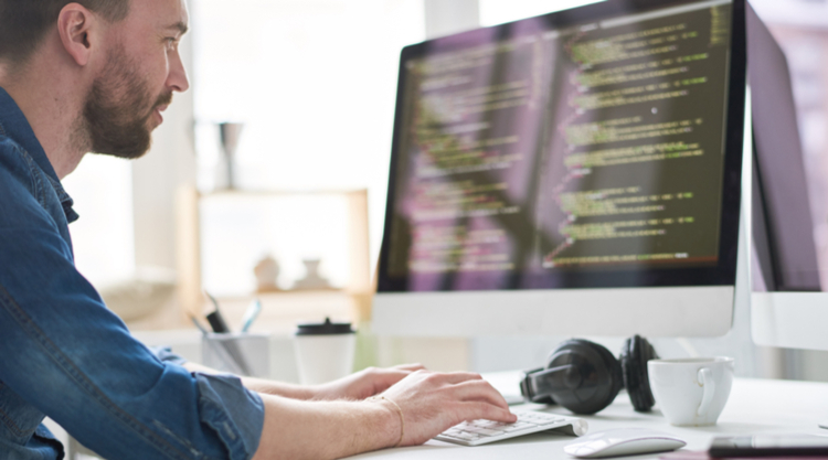 A man typing on his computer while sitting by his desk