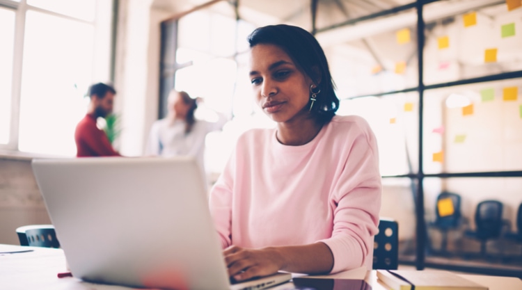 An image of a young woman seated at a table in an office space
