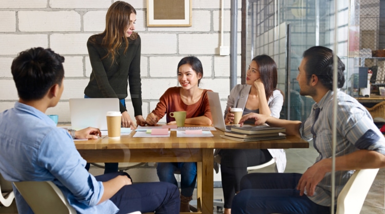 A group of co-workers seated at a conference table in an office space