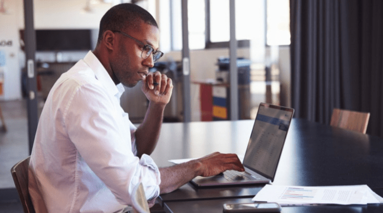 A man working on his laptop while sitting in a conference room