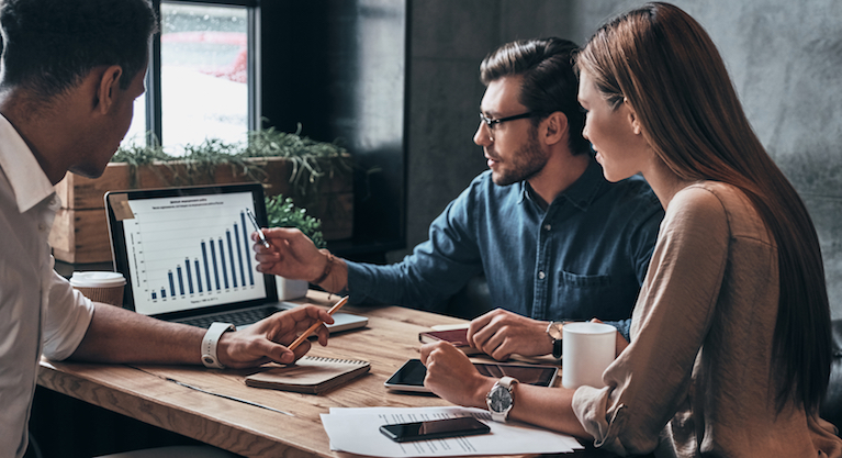 A table of men and women working in an office