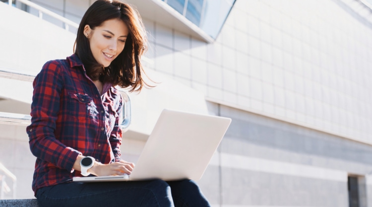 A woman sitting outside working on her laptop