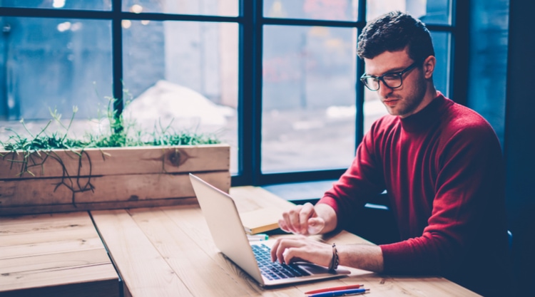 An adult man working on his laptop in a cafe