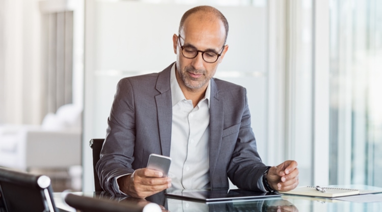 A business man looking at his cellphone and working in an office