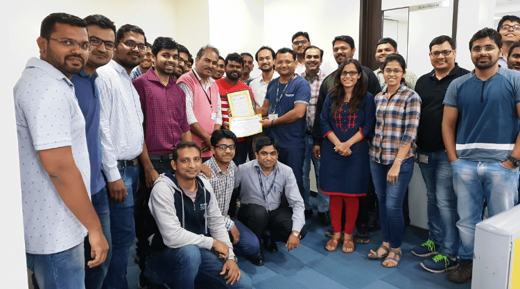 Twenty-six smiling PubMatic employees standing in their office