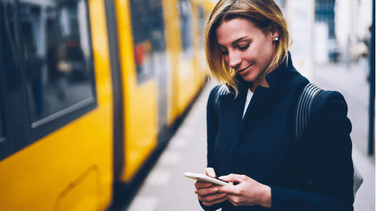 A woman using her cell phone outside of a train