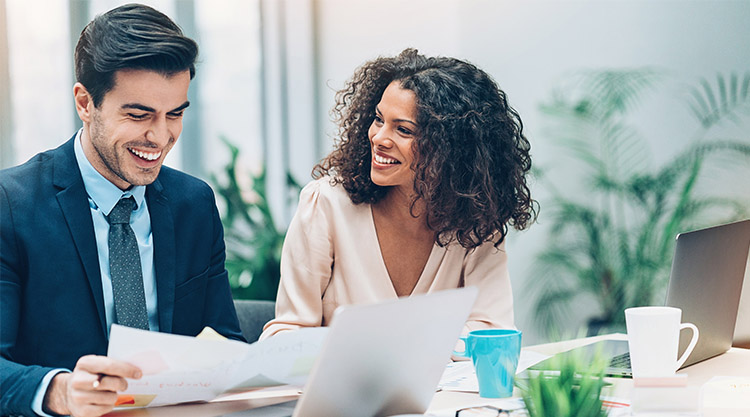 Two adults are working together in a conference while laughing