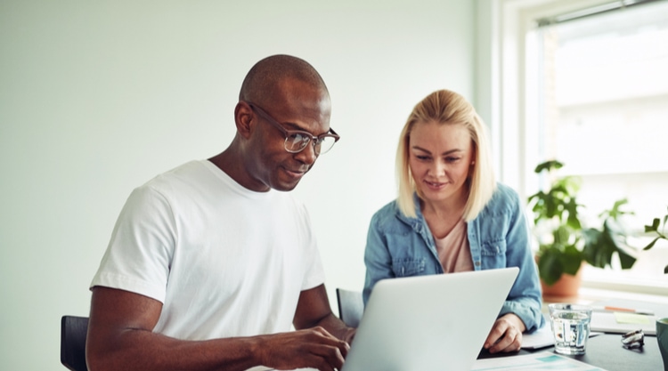 A man and woman looking at their laptop and working together in a home