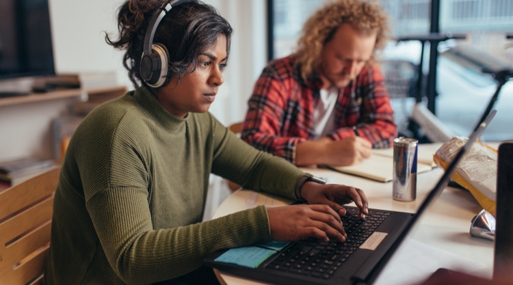 A young woman typing on her laptop in a cafe