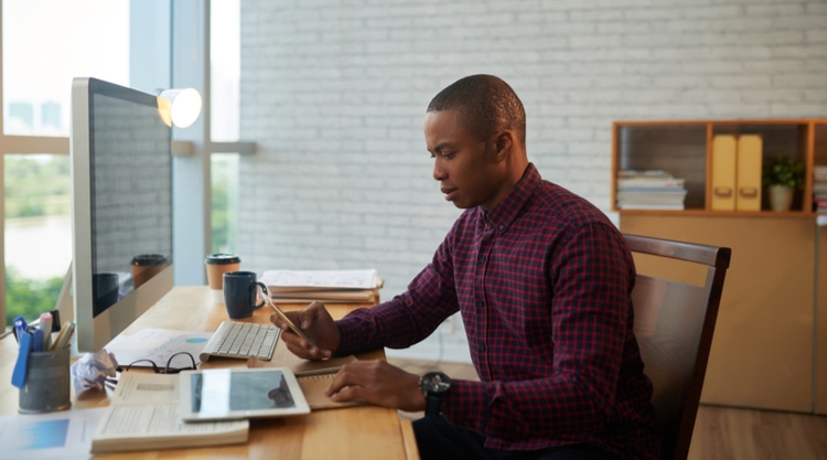 A person working at their desk looking at their cellphone