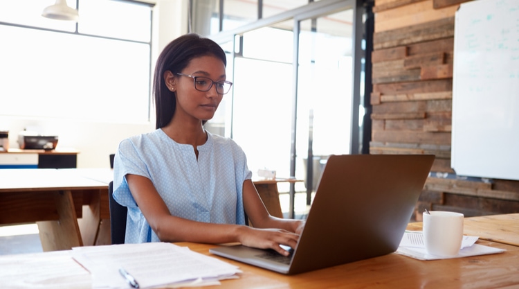 A young woman typing on a laptop in an office