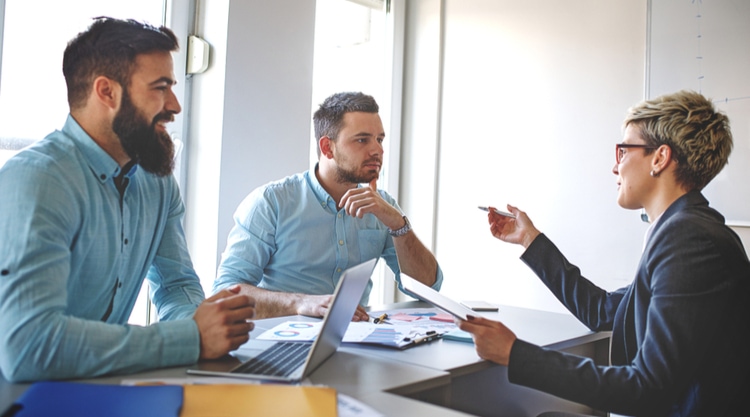 A business woman speaking to her two coworkers in an office