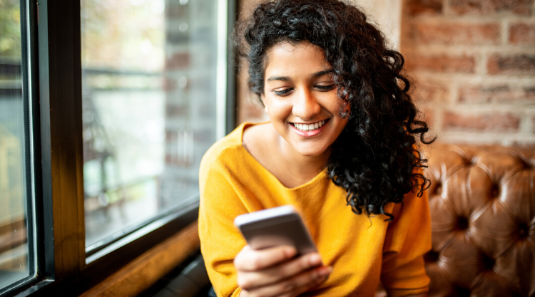 A young woman holding a cell phone while sitting on the couch