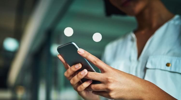 A person holding a cellphone in front of a blurred out building