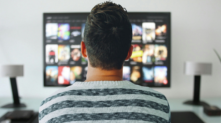 A man seated in front of a television