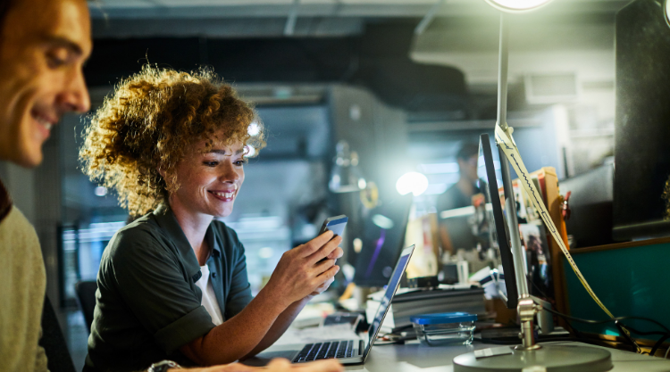 A woman looks at her phone smiling while working in an engineering lab