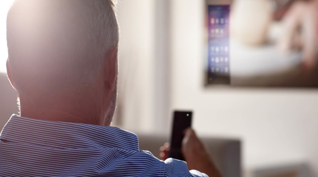 A man holding a remote control seated in his living room