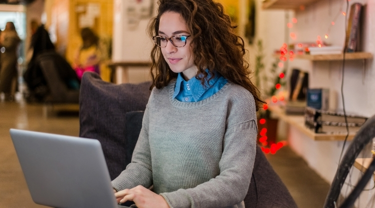 A smiling woman using her laptop in a cafe