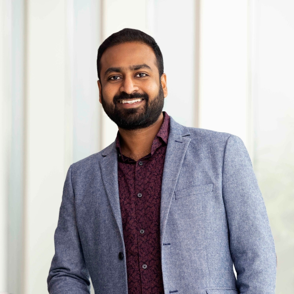 Smiling adult man in a suit standing behind a light green gradient background
