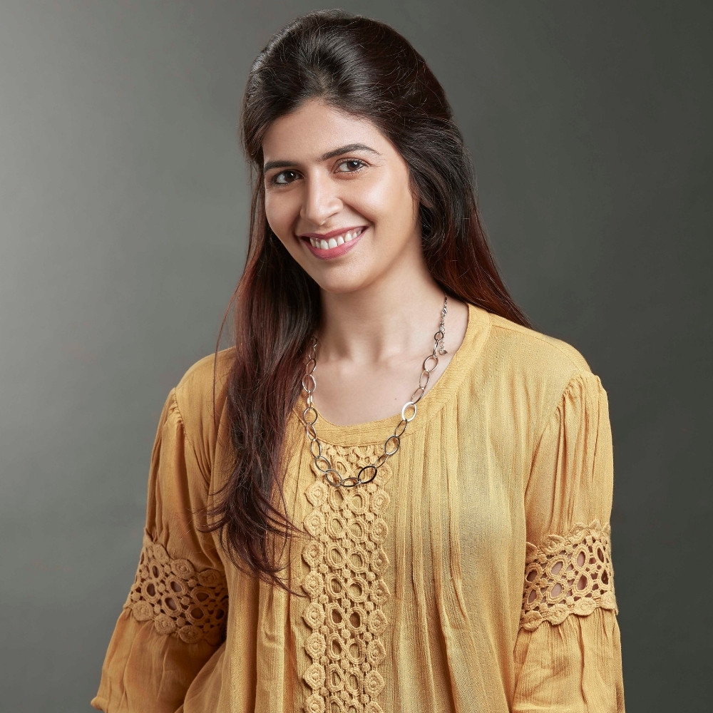 A smiling adult woman standing in front of a dusty green gradient background