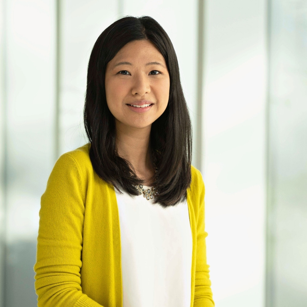 Smiling adult woman standing in front of a light green gradient backdrop
