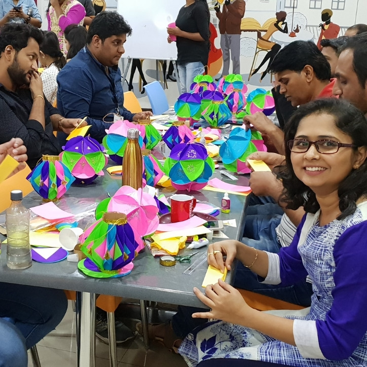 Six adults sitting at a table. There are arts and craft supplies in front of them