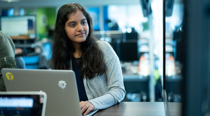 A young smiling woman using her laptop in an office