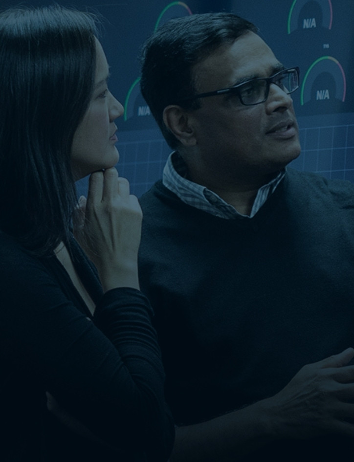 Adult woman looking at visual data on the wall and standing next to an older man looking towards it