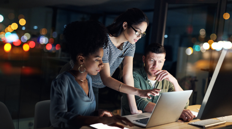 Photo of multicultural co-workers discussing work on a laptop