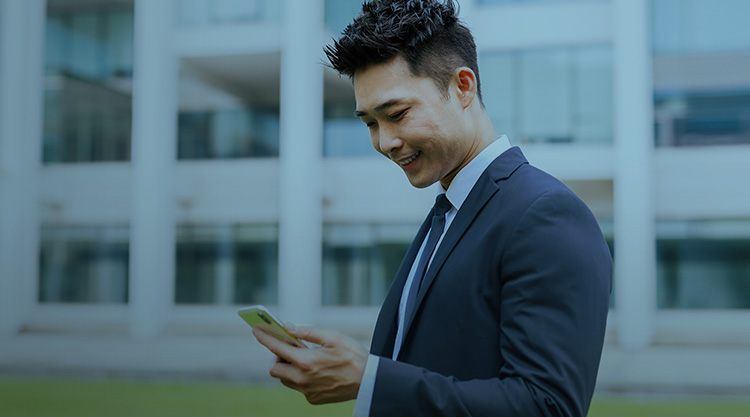 Adult man looking down at cellphone while standing outside