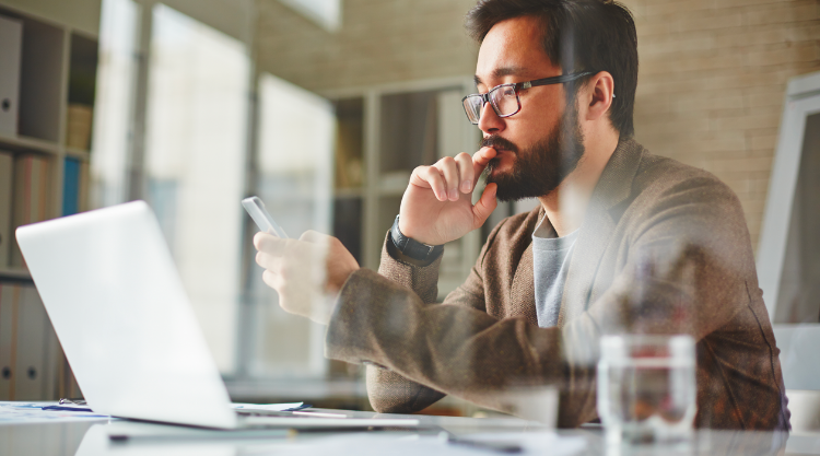 Asian man looking at phone in office