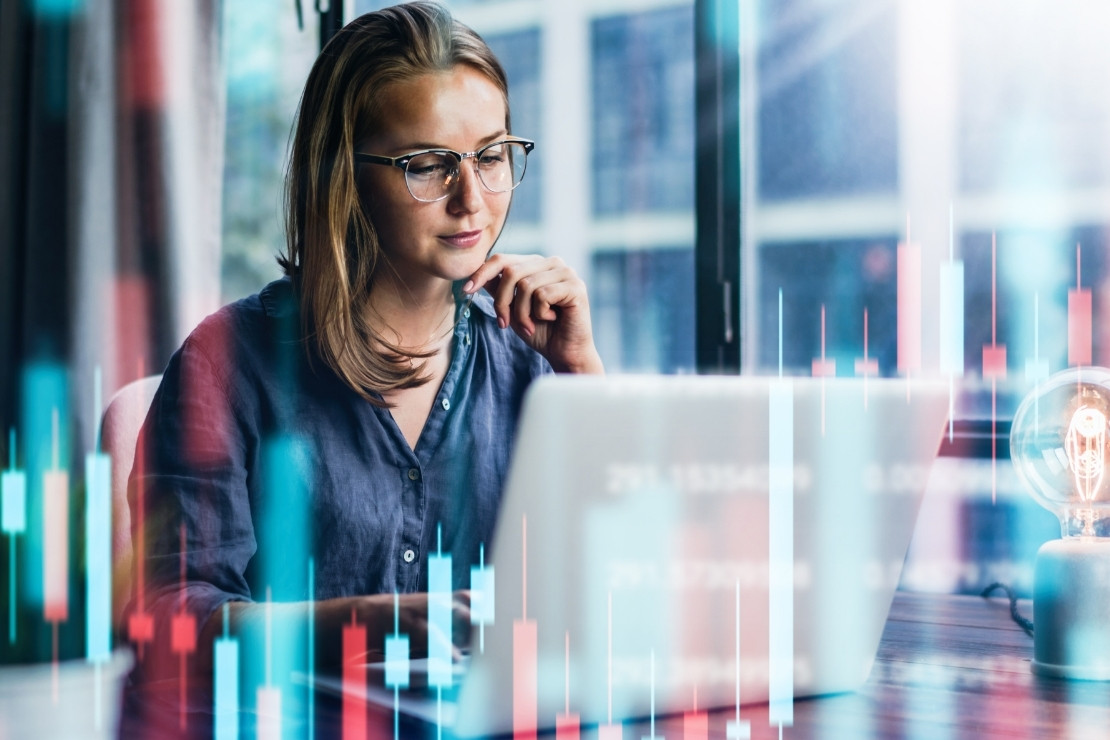 Older woman looking at laptop while sitting at her desk. There are abstract red and blue shapes over the image