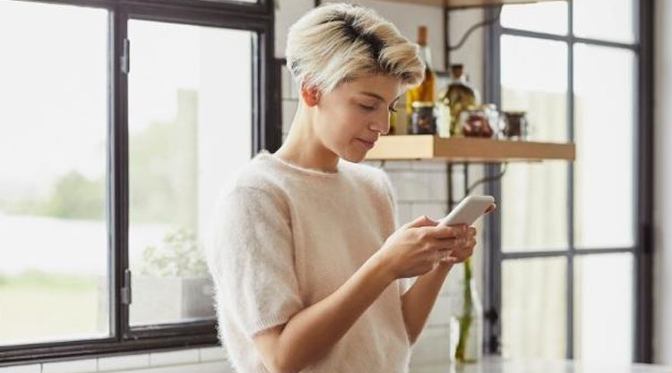 Smiling entrepreneur working from home while looking at phone