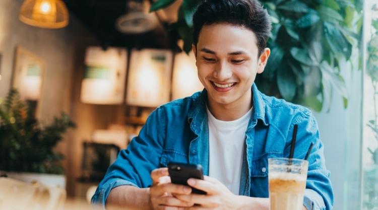 Smiling young asian man looking at phone.