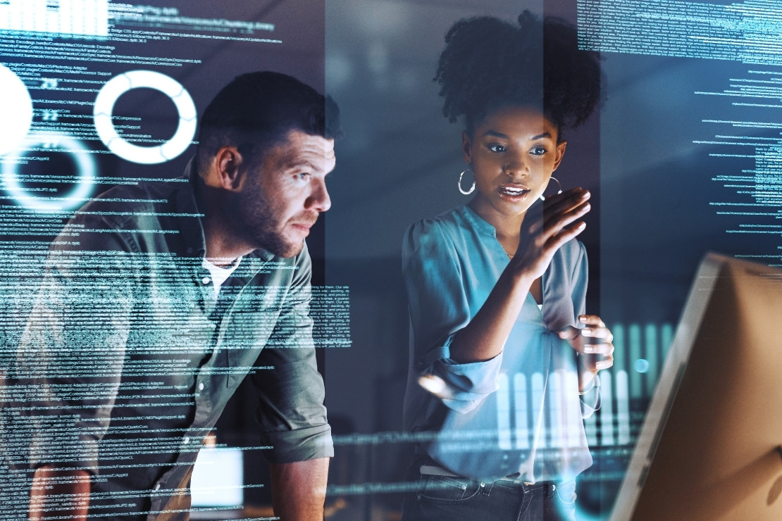 Young woman pointing at a computer desktop with an adult man leaning over and looking at the screen. There is data and text floating on top of the image