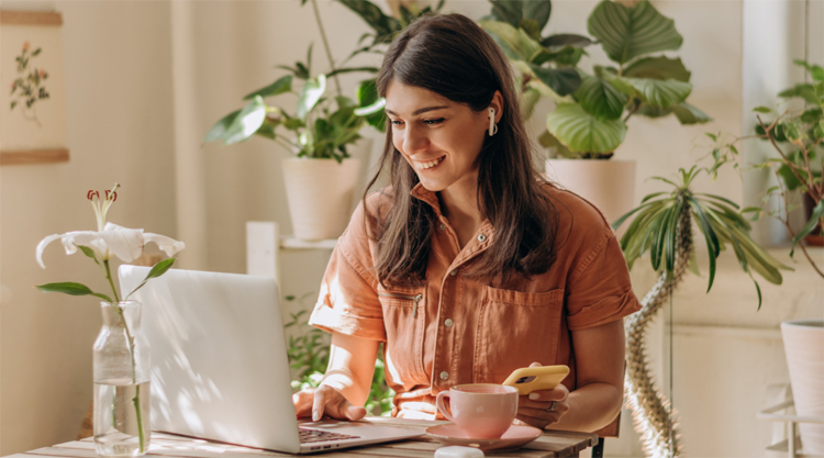 Positive young mixed race woman using a laptop and smartphone at home.