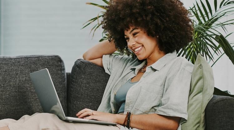A young woman sitting alone on her sofa at home and using her laptop