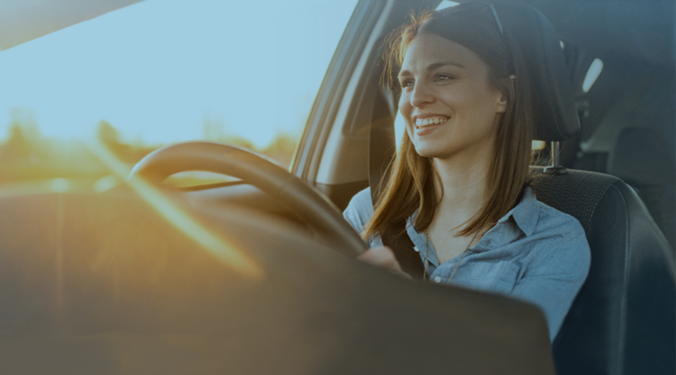 Smiling adult woman driving a car through a town