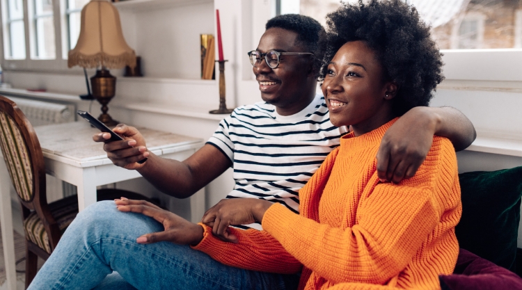 Happy African - American couple having fun watching TV