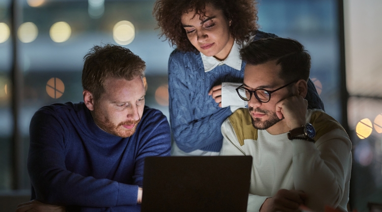 A group of coworkers gaze at a laptop